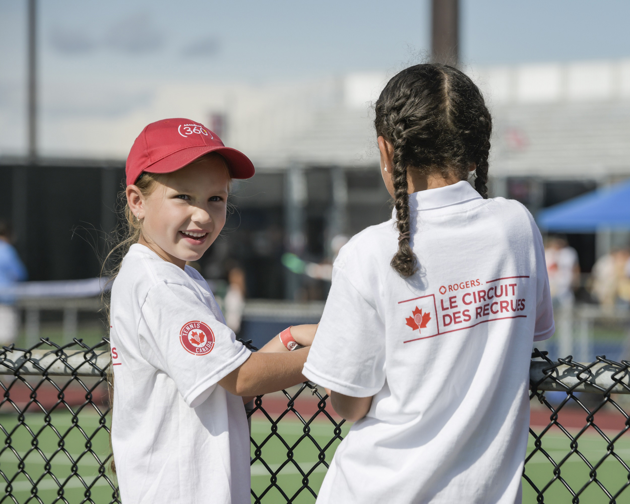 Two children posing in front of a tennis court