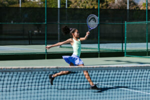An action photo of a young girl swinging a tennis racket