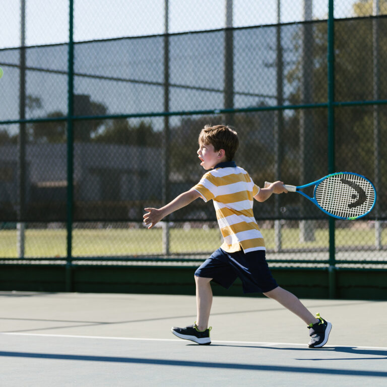 A young in striped shirt, swinging a tennis racket